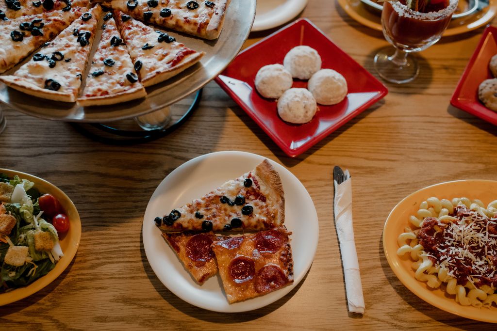 assortment of pizza, pasta, salad and beer